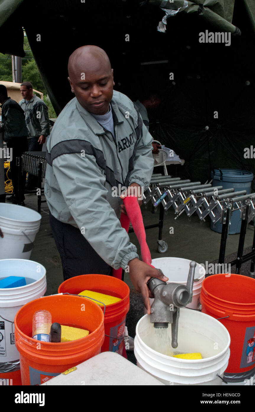 Ein CBRN-Spezialist der US Army bei der 411th Chemical Company nimmt an einer Massendekontamination Teil, bei der Wassereimer für ein ambulantes Zelt gefüllt werden. Die Übung umfasst JROTC-Schüler, Armee-Reserve-Einheiten und lokale Rettungsdienste, um die Zusammenarbeit, die Vorbereitung und die Reaktionsfähigkeit aufzubauen. Stockfoto