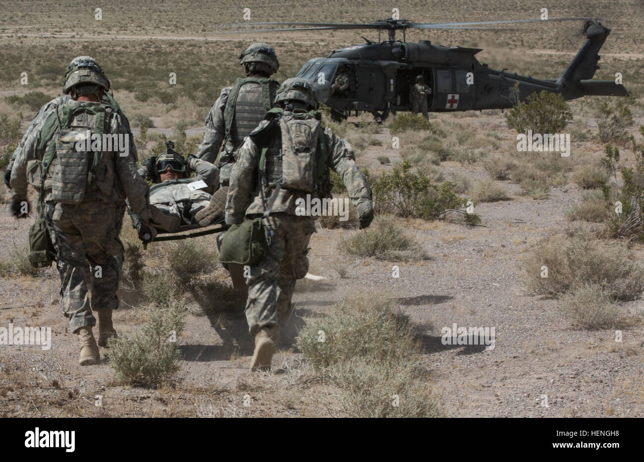 FORT IRWIN, Kalifornien-Soldaten der US Army, Charlie Troop zugewiesen, 2. Bataillon, 11. Feldartillerie-Regiment tragen Verwundeten Personal ein UH-60 Blackhawk während der entscheidenden Aktion Rotation 14-07 im National Training Center, 17. Mai 2014. Die zweiwöchige Ausbildung Rotation bietet eine live, virtuelle und konstruktive Ausbildung Umgebung, so dass Einheiten, ihre taktischen und technischen Fertigkeiten in vollem Umfang auszuüben.  (Foto: US-Armee Sgt. Richard W. Jones Jr., Operations Group, National Training Center) Soldaten engagieren feindliche Ziele mit Haubitze und retten den Verwundeten 140517-A-QU939-752 Stockfoto