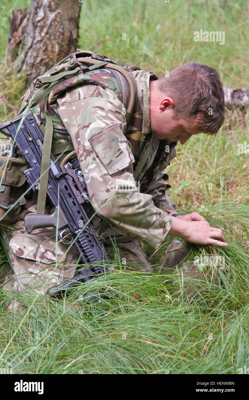Britische Armee Royal Military Academy Sandhurst jüngsterer Sohn Michael Harrison fügt Rasen um seinen Helm zu tarnen, bevor man durch individuelle live-Feuer-Übungen. Sandhurst und Military Academy in West Point Kadetten absolvierte ihren zweiten Tag einer gemeinsamen zweiwöchigen Feld Übung mit live-Heißausbildung. Die Übung bestand aus einzelnen und Kader Bewegungen auf Palette 204 auf dem Truppenübungsplatz Grafenwöhr in der US-Armee 7. Armee Joint Multinational Training Command, Juli 8. Kadetten aus Sandhurst sind ihre letzte Feld Übung und 50 West Point Kadetten absolvieren ihre Führung d Stockfoto