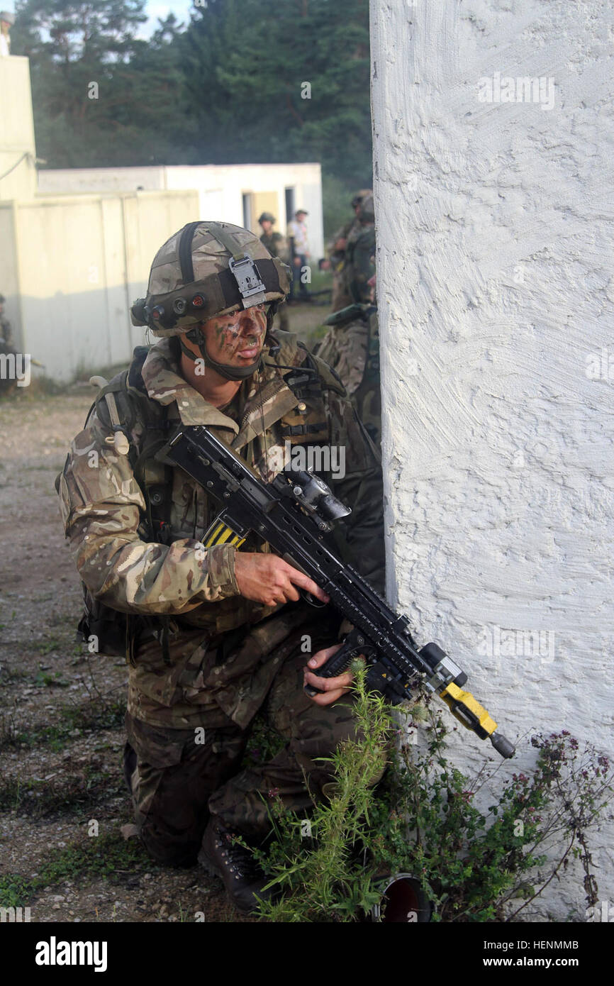 Britische Armee Royal Military Academy Sandhurst und US Military Academy in West Point Kadetten wachte vor Sonnenaufgang, Dorf-Clearing Manöver am Truppenübungsplatz Hohenfels, 15. Juli 2014 anzugehen. Die Kadetten haben seit dem 7. Juli in der US-Armee 7. Armee gemeinsame Multinational Training Command in Grafenwöhr und Hohenfels Übungsplätze trainiert. Sandhurst Kadetten absolvieren ihre letzte Übung vor Graduierung und der West Point Kadetten ihre Ausbildung von Führungskräften Entwicklung abgeschlossen werden. (Foto: US-Armee Sgt. Christina M. Dion, 319th Mobile Public Affairs-Abteilung) Sandhurst, Stockfoto