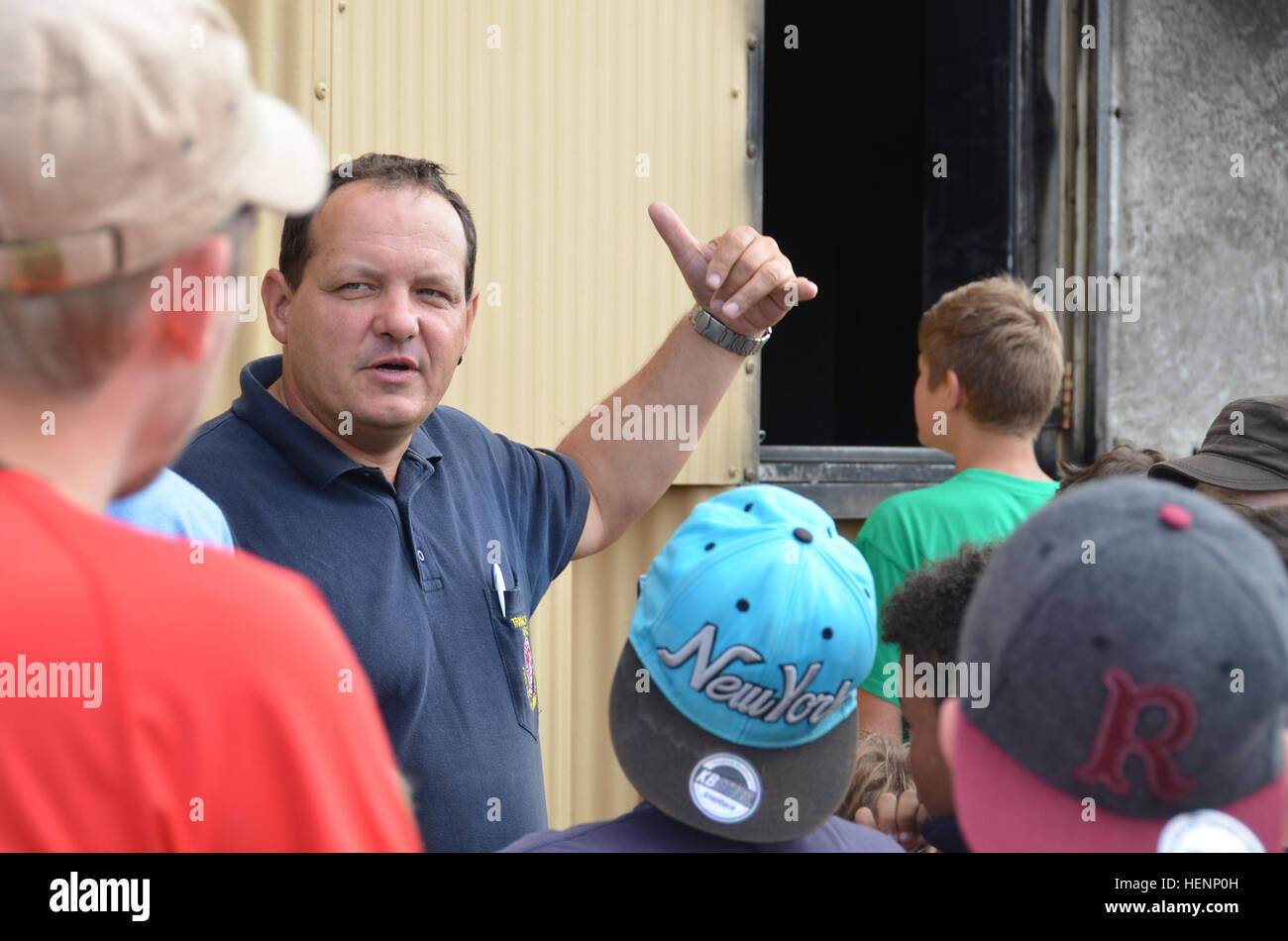 Juergen Schwab, Ausbildungsleiter, erläutert den Zweck der Feuerwehrmann Ausbildungsstätte am Urlas Gehäuse. Jungen von einem Sommer-Camp in Sielmingen Filderstadt, Deutschland, besuchte die Feuerwehr Training Center am US Army Garrison Ansbach Urlas Housing 7. August 2014. Schwab führte die Kinder durch ihre Feuerwehrfahrzeuge sowie Einrichtungen, die Gebäude Feuer zu simulieren. Nach der Tour aßen die Kinder im Gehäuse Urlas Foodcourt. (US Armee-Foto von Bryan Gatchell, USAG Ansbach Public Affairs) Training vor Ort 140807-A-FC388-001 Stockfoto