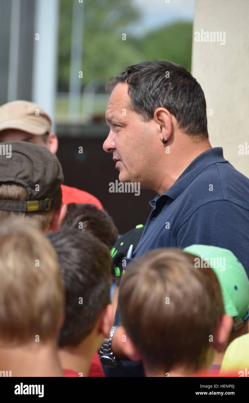 Juergen Schwab, Feuerwehrmann Ausbildungsleiter, erläutert die Verwendung der Brandbekämpfung Ausbildungsstätte. Jungen von einem Sommer-Camp in Sielmingen Filderstadt, Deutschland, besuchte die Feuerwehr Training Center am US Army Garrison Ansbach Urlas Housing 7. August 2014. Schwab führte die Kinder durch ihre Feuerwehrfahrzeuge sowie Einrichtungen, die Gebäude Feuer zu simulieren. Nach der Tour aßen die Kinder im Gehäuse Urlas Foodcourt. (US Armee-Foto von Bryan Gatchell, USAG Ansbach Public Affairs) Feuer Schulungseinrichtung 140807-A-FC388-002 Stockfoto
