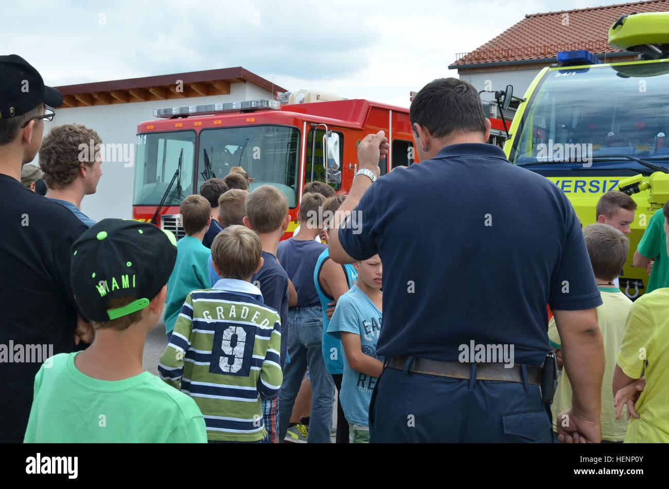 Juergen Schwab, Brandbekämpfung Ausbildungsleiter, spricht über die Feuerwehrfahrzeuge auf der Trainingsanlage am Urlas Gehäuse. Jungen von einem Sommer-Camp in Sielmingen Filderstadt, Deutschland, besuchte die Feuerwehr Training Center am US Army Garrison Ansbach Urlas Housing 7. August 2014. Schwab führte die Kinder durch ihre Feuerwehrfahrzeuge sowie Einrichtungen, die Gebäude Feuer zu simulieren. Nach der Tour aßen die Kinder im Gehäuse Urlas Foodcourt. (US Armee-Foto von Bryan Gatchell, USAG Ansbach Public Affairs) Feuerwehr 140807-A-FC388-009 Stockfoto