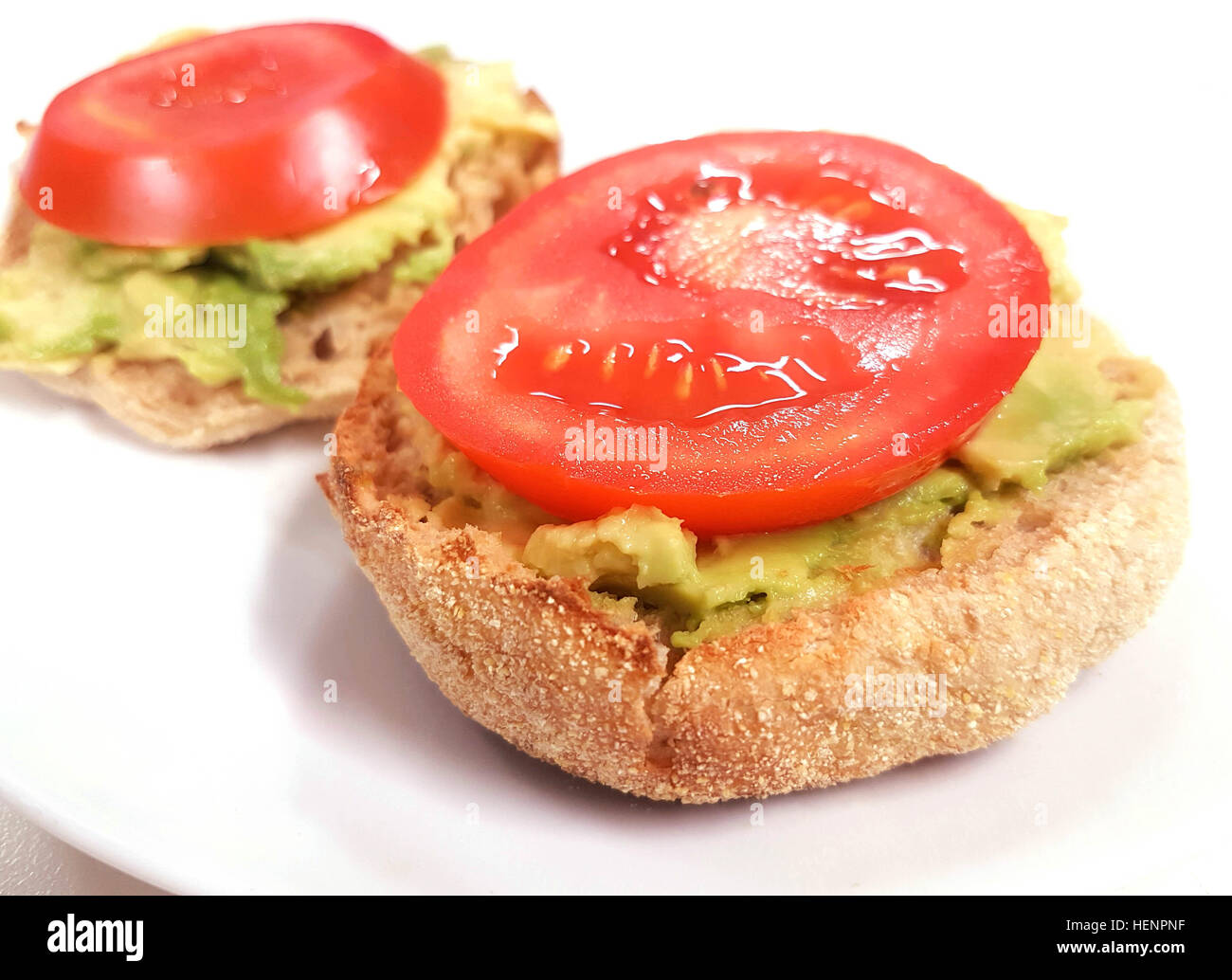 schnell und einfach leckere englische Muffins mit Ausbreitung Avocado und Tomaten an der Spitze Stockfoto