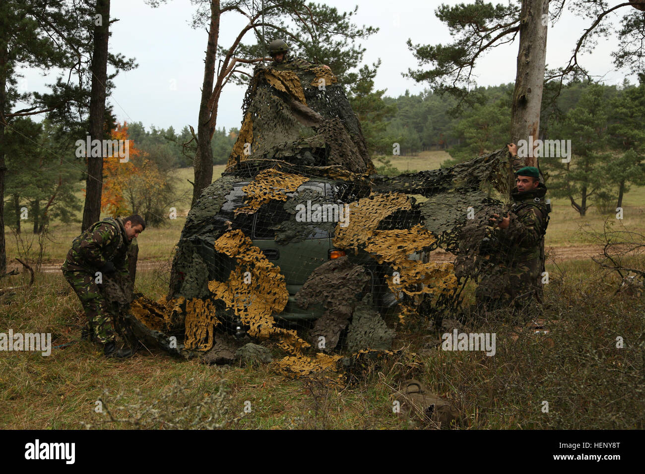 Rumänische Soldaten decken ein Fahrzeug mit Tarnung während des Trainings kombiniert Entschlossenheit III bei der Joint Multinational Readiness Center in Hohenfels, Deutschland, 7. November 2014.  Kombinierte Lösung III ist eine multinationale Übung, die enthält mehr als 4.000 Teilnehmer aus NATO und Partner, und soll eine komplexe Trainingsszenario bieten, die konzentriert sich auf multinationale unified Land Operationen und das US-Engagement für NATO und Europa verstärkt. (US Armee-Foto von Spc. John Kresse Jr./freigegeben) Kombinierte Lösung III 141107-A-AO034-010 Stockfoto