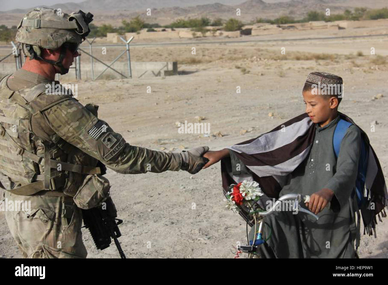 SPC. Brad Falde, Headquarters und Headquarters Troop, 5. Staffel, 1. Kavallerie-Regiment, 1st Stryker Brigade Combat Team, 25. Infanterie-Division, schüttelt eine afghanische Kinder Hand. Der junge ist auf dem Weg zum ersten Tag der Schule im Stadtteil Shah Wali Kot. (Foto: U.S. Army: Capt. Michael Newman 5/1 CAV UPAR) Afghanische Kinder umarmen neues Schuljahr 110921-A-BE343-001 Stockfoto