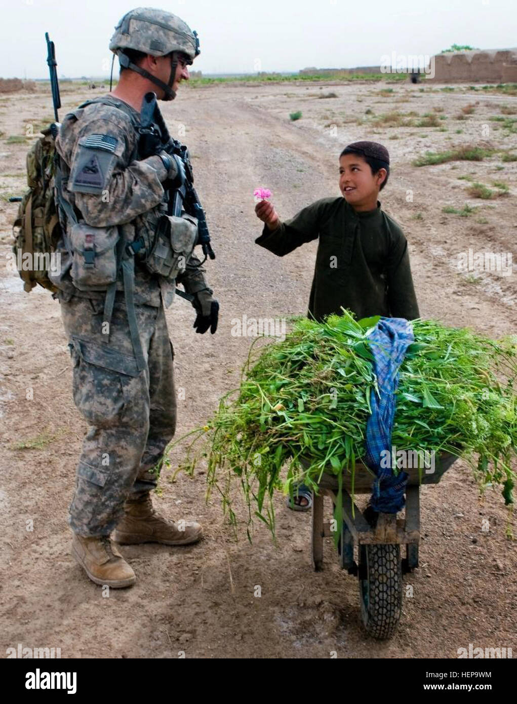 Ein afghanische Kind bietet eine Blume an US Armee Sgt. John M. Davis, Teamleiter für 3rd Platoon, Mad Dog-Truppe, 4. Staffel, 2. Stryker Cavalry Regiment aus Vilseck, Deutschland, während einer Patrouille in der Nähe von Kandahar Flugplatz, Afghanistan, 14. April 2011. Davis, ein Pocatello, Idaho, heimisch, hat eine arbeiten-Kompetenz der Pashto, eines der wichtigsten Sprachen in Afghanistan, und spricht oft mit Kindern während Patrouillen. 2SCR Zug gewinnt Vertrauen und Vertrauen der Menschen in Afghanistan 390818 Stockfoto