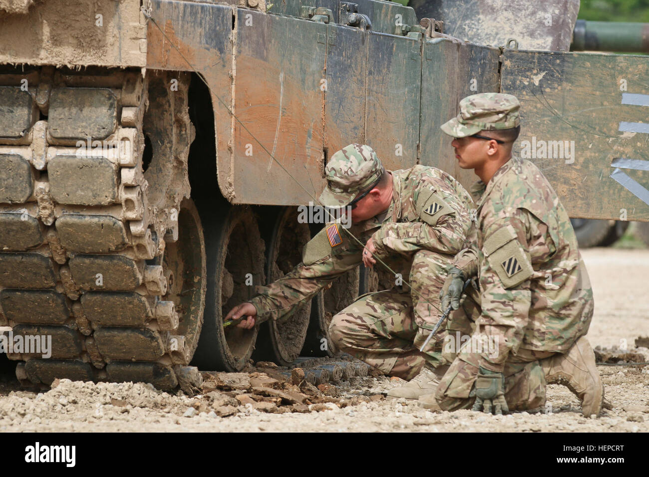 US Armee Sgt. Barry Greg und Pfc. Jovanny Colon, beide M1 Rüstung Crewman in die 1. gepanzerte Brigade Combat Team, 3. Infanterie-Division, kratzt den eingebetteten Schlamm aus Roll-Räder auf einem M1A2 Abrams Kampfpanzer nannten persönlich Deimos nach dem griechischen Gott des Krieges, 12. Mai 2015 bei der Armee Truppenübungsplatz Hohenfels, Deutschland. Greg erklärt, dass wenn sie wirksam im Kampf sein, dann müssten während der routinemäßigen vorbeugende Wartungen und Dienstleistungen oder PMCS, vor der Überschrift in dem Truppenübungsplatz Hohenfels für Manöver-Übungen im Rahmen des kombiniert zu beheben IV gewinnen. Combi Stockfoto