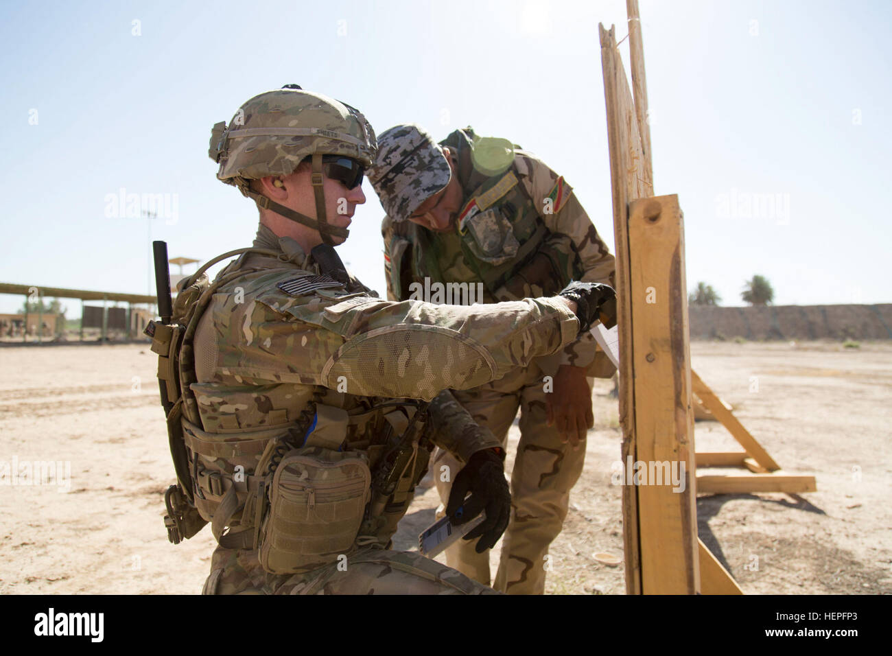 US Armee Sgt. Jeffrey Sheets, Fallschirmjäger, Alpha-Truppe, 5. Staffel, 73. Kavallerie-Regiment, 82nd Airborne Division zugewiesen inspiziert ein Ziel für eine irakische Soldaten, die 73. Brigade, 16. Division, während ein Schießstand am Camp Taji, Irak, 21. Juni 2015 zugewiesen. Bis heute wurden mehr als 2.100 Soldaten der irakischen Sicherheitskräfte am Camp Taji als Teil der kombiniert Joint Task Force – Betrieb innewohnende lösen multinationale Bemühung des islamischen Staates im Irak und der Levante zu besiegen geschult. (Foto: US-Armee Sgt. Charles M. Bailey, CJTF-OIR Public Affairs) Irakische Armee 73. Brigade Bereich, Op Stockfoto