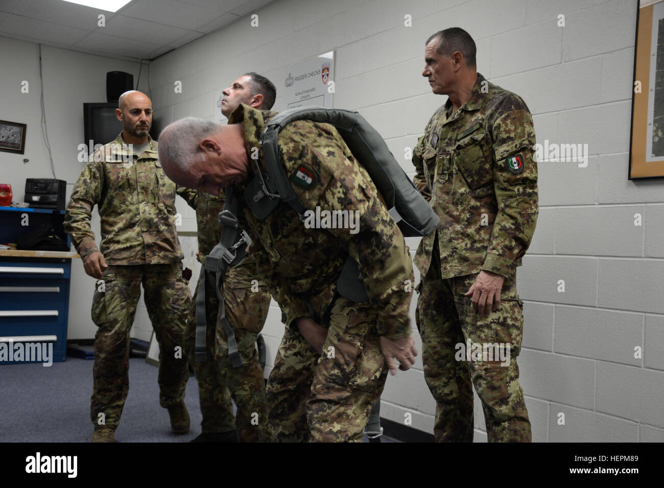 Italienische Major General Enrico Pollini der Associazione Nazionale Paracadutusti D'Italia stellt auf der US-Armee Notfall Bail-Out Anzug während andere italienische Soldaten warten zu unterstützen in Fort Bragg, N.C., 11. November 2015. USA und Partner Nation Soldaten trainieren für luftgestützte Operationen zur Unterstützung der Operation Spielzeug fallen. (US Armee-Foto von Pfc. Darion Gibson/freigegeben) Betrieb Spielzeug Tropfen 151130-A-JW364-014 Stockfoto