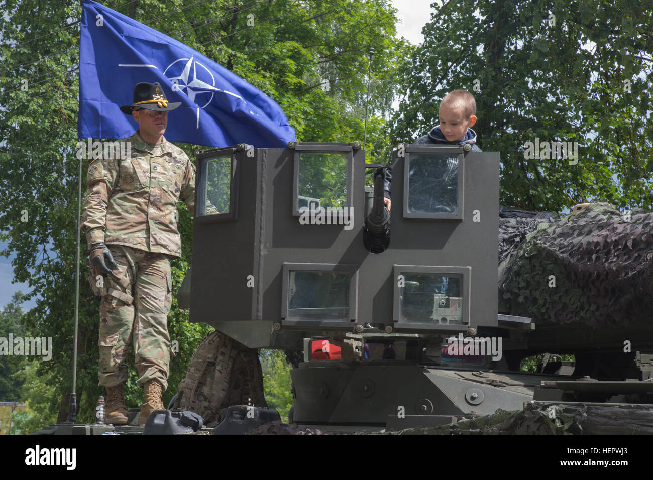 US Armee Sgt. 1. Klasse Christopher Price beobachtet, wie ein Lokalmatador an der "Gunners" Turm von seiner Stryker Armored Fighting Vehicle beim Neuaufbau von 4. Geschwader, 2. Kavallerie-Regiment in einem Park in Litauen Kupiskis 12. Juni 2016, während Dragoon Ride II, 2.200 Kilometer Konvoi nach Estland für Übung Saber Strike 16 statische Anzeige sitzt. Übung Saber Strike 16 ist ein unter der Leitung von US-Army in Europa kooperative Übung zur Verbesserung der gemeinsamen Interoperabilität zur Unterstützung multinationaler Einsätze. (US Armee-Foto von Staff Sgt. Ricardo HernandezArocho/freigegeben) Säbel-Strike 2016 Konvoi Stockfoto