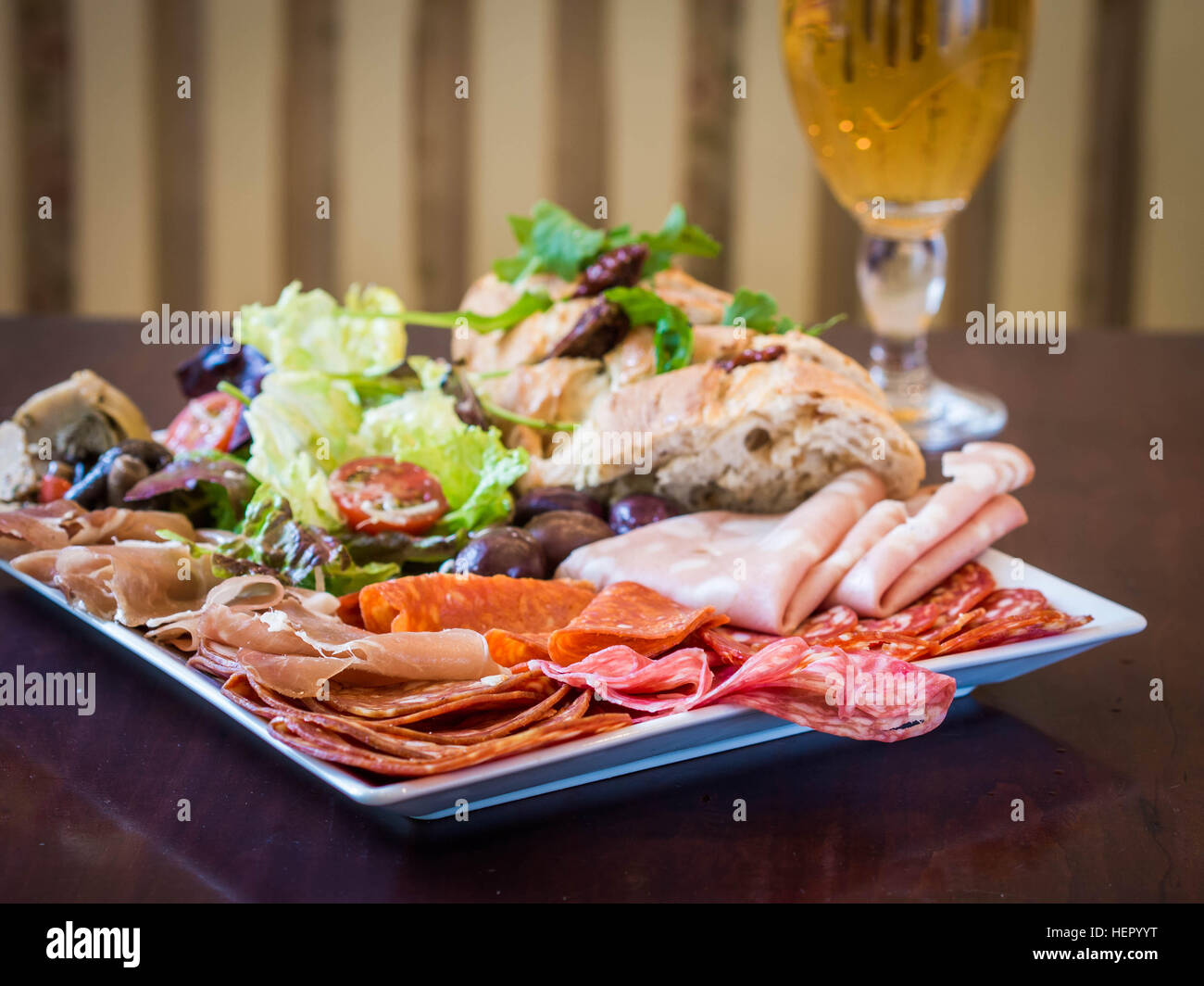 Wurst, Salat, Brot und Oliven mit Glas Bier Stockfoto