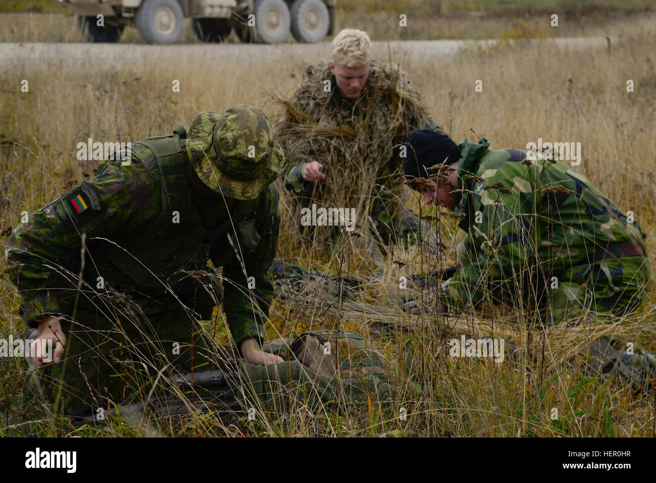 Ein litauischer Soldat (links) und schwedische Soldaten (rechts) verwenden in der Nähe Rasen anpassen ihre Ghillie-Anzüge und tarnen ihre Waffen vor der Teilnahme an dem stalking Herausforderung der Europäischen besten Sniper Squad Wettbewerb am 7. Armee Training Command, Truppenübungsplatz Grafenwöhr, Bayern, Deutschland, 26. Oktober 2016. Die beste Sniper Squad Europapokal ist ein Army Europe-Wettbewerb herausfordernde Militärs aus in ganz Europa zu konkurrieren und verbessern die Zusammenarbeit mit Verbündeten und Partnerstaaten. (Foto: U.S. Army Spc. Emily Houdershieldt) Europäische beste Sniper Squad Wettbewerb 2016 161026-A-U Stockfoto