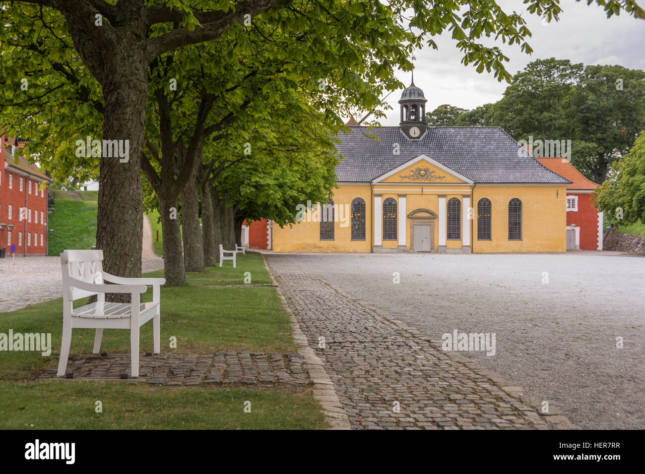 Die gelbe Kirche des Kastelkirken innerhalb der Kastellet in Kopenhagen einen Platz vor mit roten Zeilen der Kaserne. Stockfoto