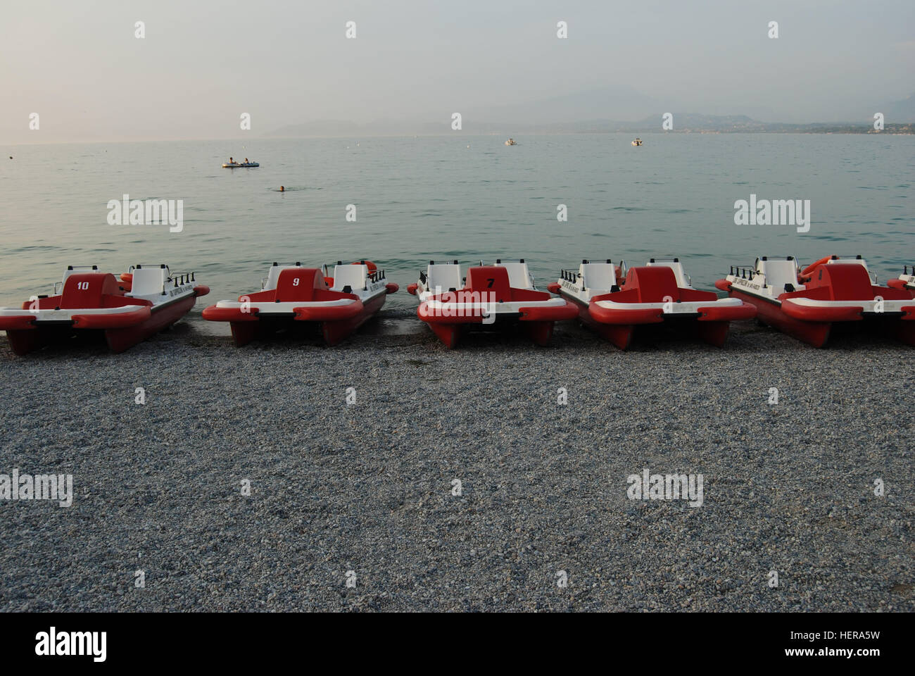 FÃ¼nf Rot-weiÃŸe Tretboote Stück in Einer Reihe bin Kieselstrand Bei Peschiera Stockfoto