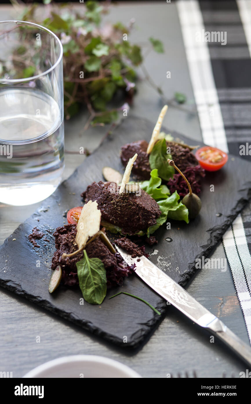 Oliven Tapenade Starter mit Glas Wasser Stockfoto
