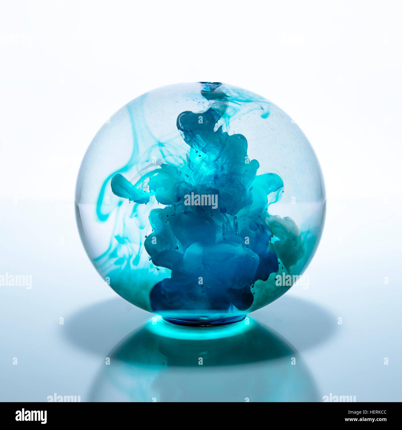 Kristallkugel mit blauer Aquarellfarbe in Wasser gefüllt Stockfoto