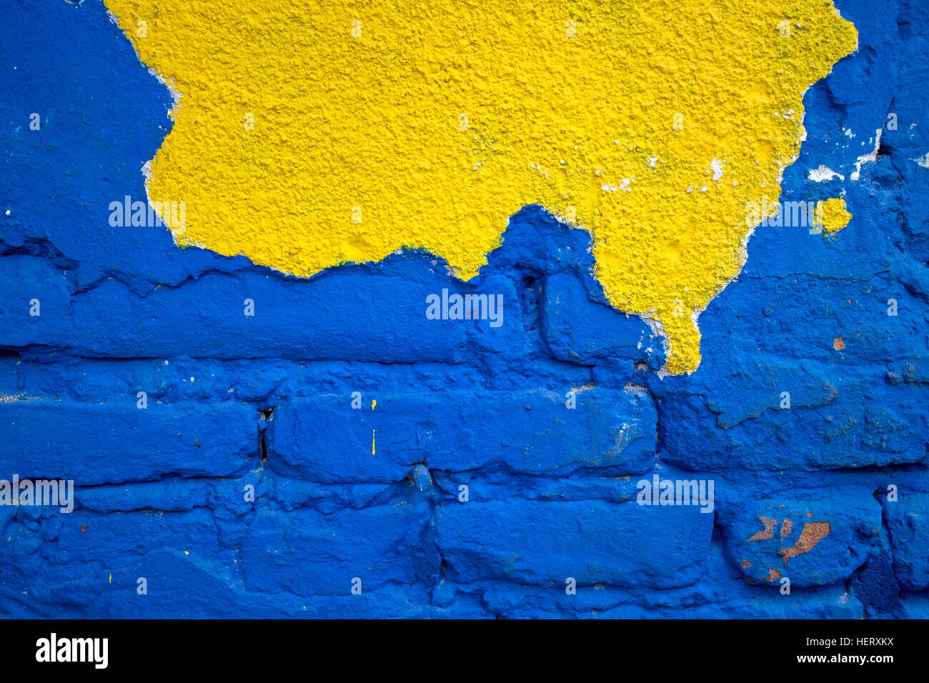 Alte Mauer mit gerissenen gelbe Fassade und blauen Malerei Ziegel Stockfoto