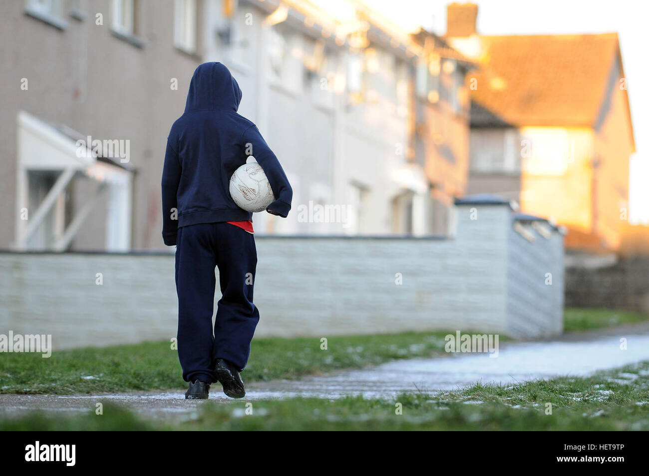Ein Junge geht auf einem schneebedeckten Weg auf dem Gurnos er Housingl Anwesen in Merthyr Tydfil, South Wales, UK. Stockfoto