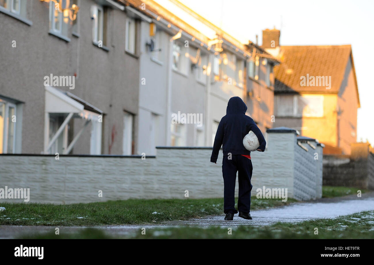 Ein Junge geht auf einem schneebedeckten Weg auf den Gurnos Rat Wohnsiedlung in Merthyr Tydfil, South Wales, UK. Stockfoto