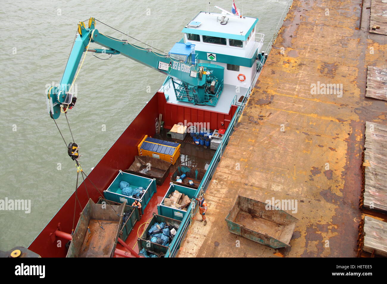 Müll-Boot neben einem großen Schiff, das Sammeln von Müll in den Hafen von Rotterdam, die Niederlande Stockfoto
