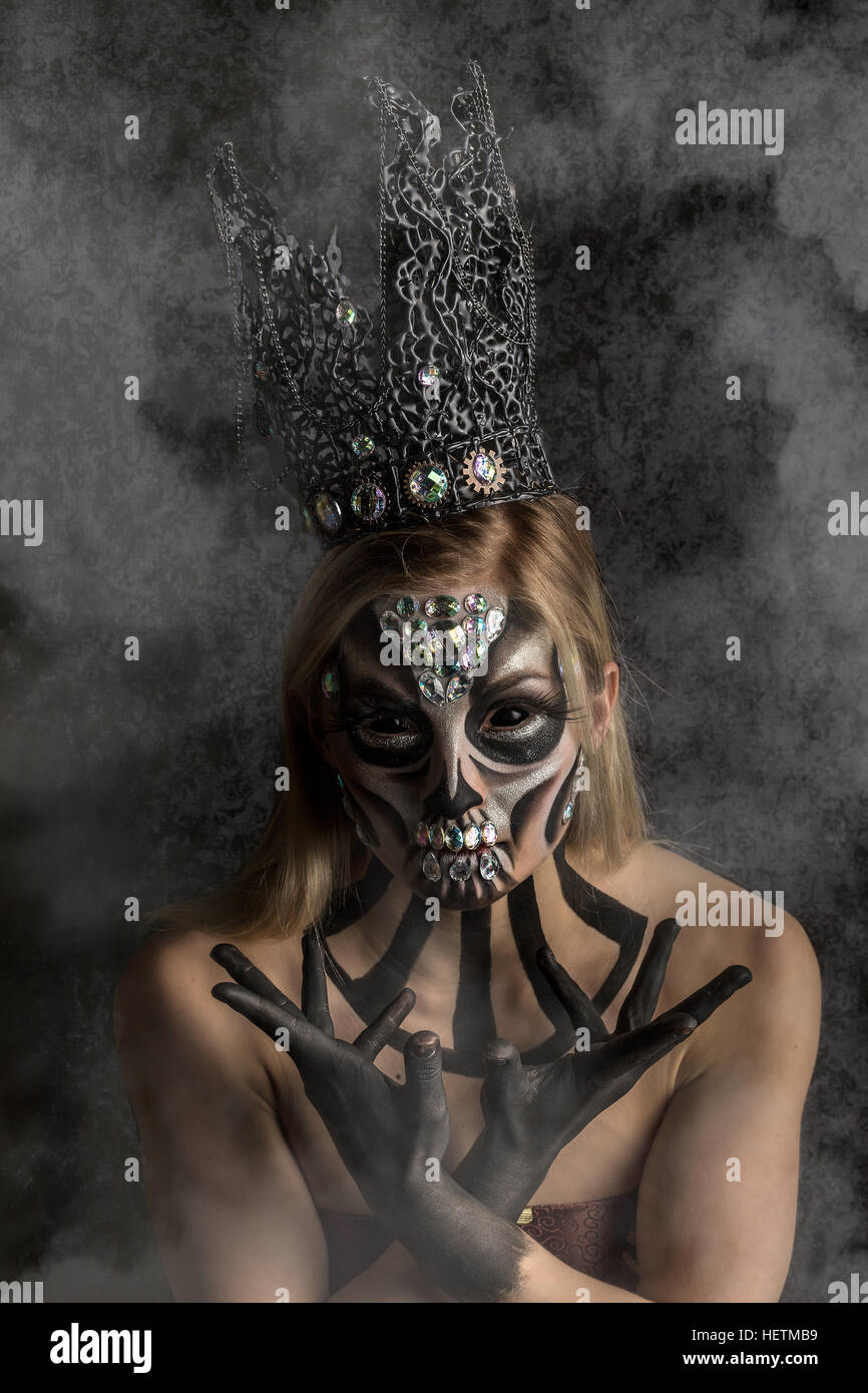 Tag der Toten schimmernden kreative Make-up in Candy-Schädel-Stil mit silbernen Perlen und gotische Krone Kopfbedeckung, gesehen durch Rauch Stockfoto