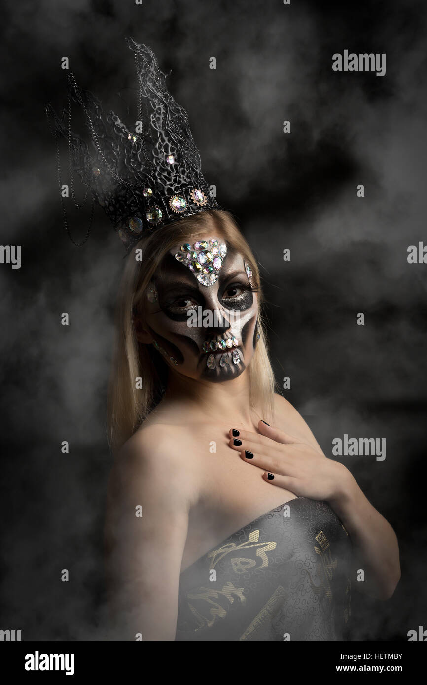 Tag der Toten schimmernden kreative Make-up in Candy-Schädel-Stil mit silbernen Perlen und gotische Krone Kopfbedeckung, gesehen durch Rauch Stockfoto
