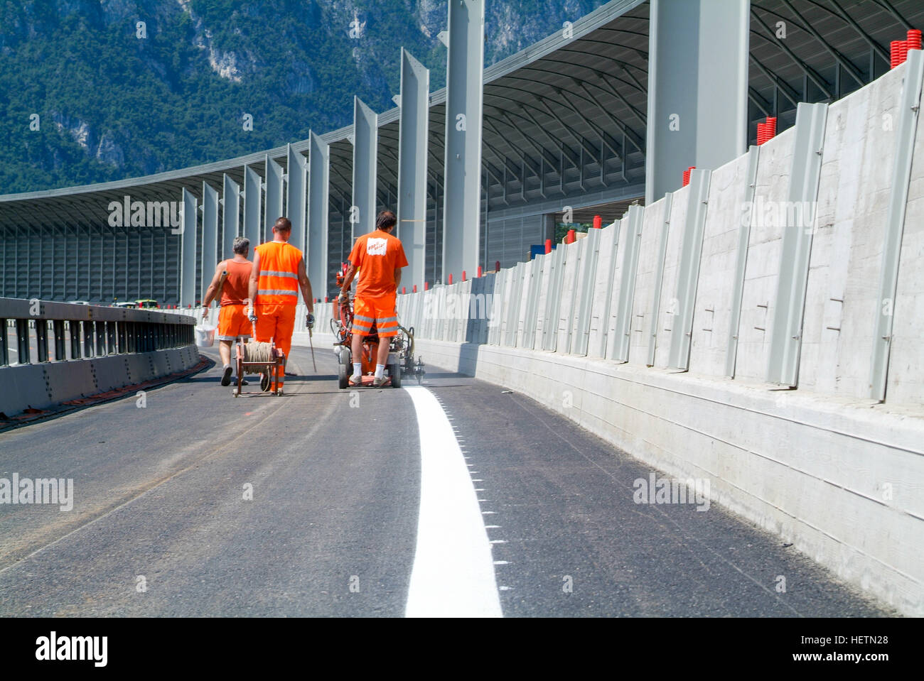 Bissone, Schweiz - 20. Juni 2011: Maschine ausgeworfen und Arbeiter auf der Straße und Verkehr melden Malerei Stockfoto