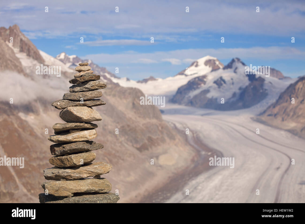 Ein Stein Cairn in den Bergen in der Schweiz. Der Aletsch-Gletscher und die Berge Eiger und Mönch sind im Hintergrund zu sehen. Der Stein im Fokus Stockfoto