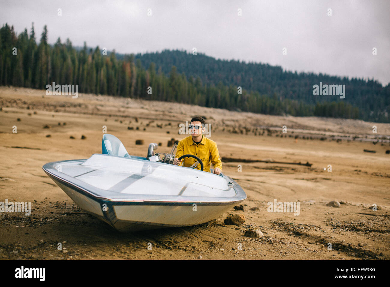 Junger Mann sitzt im gestrandeten Schnellboot, Huntington Lake, Kalifornien, USA Stockfoto