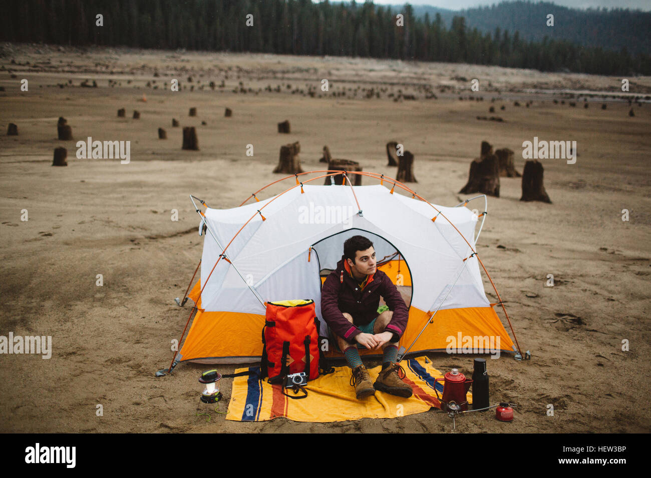 Junger Mann sitzt im Zelt am Strand, Huntington Lake, Kalifornien, USA Stockfoto