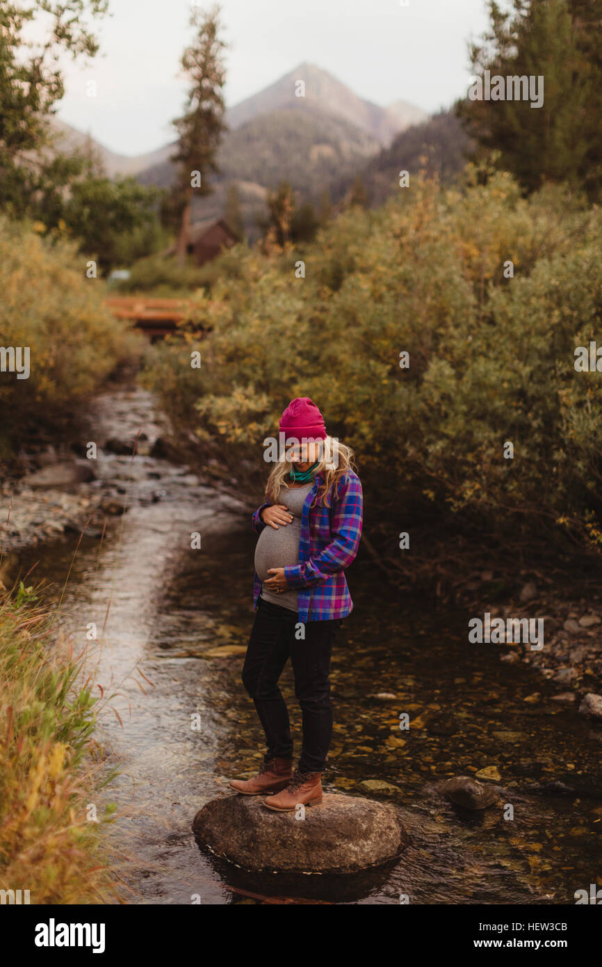 Schwangere Frau, stehend am Rock Creek, hält Magen, Mineral King, Sequoia Nationalpark, Kalifornien, USA Stockfoto