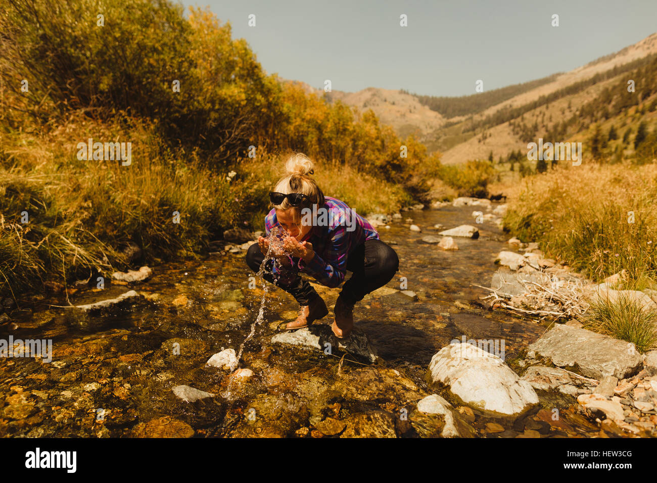 Frau kauert, Trinken von Creek, Mineral King, Sequoia Nationalpark, Kalifornien, USA Stockfoto