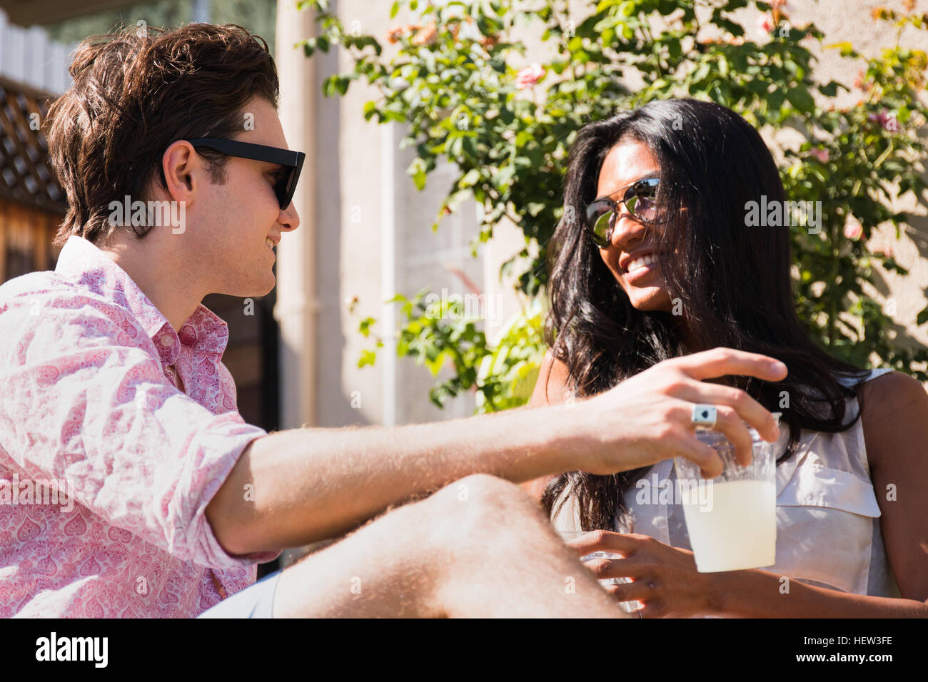 Junges Paar im Freien entspannen, hält Getränke Stockfoto
