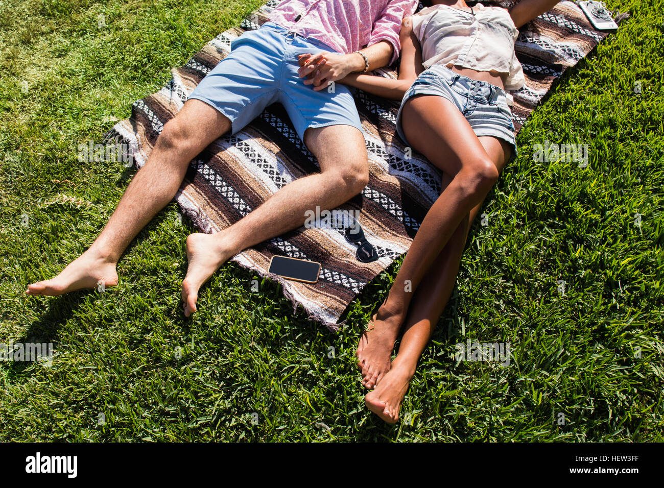 Junges Paar entspannen im Freien, auf der Decke auf dem Rasen liegen, Hand in Hand, niedrige Abschnitt Stockfoto