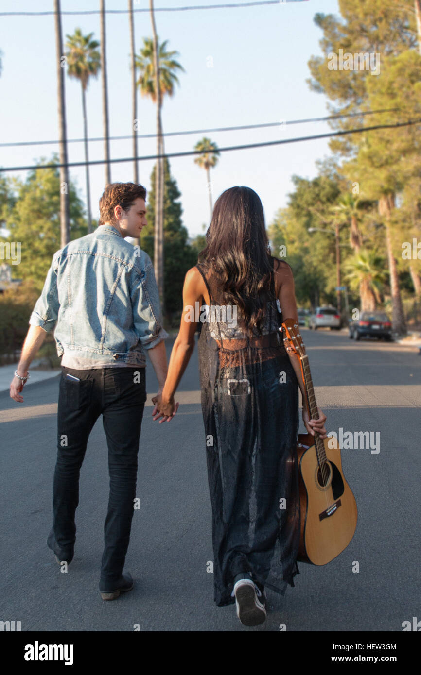 Junges Paar walking im Freien, junge Frau Holding Gitarre, Rückansicht Stockfoto