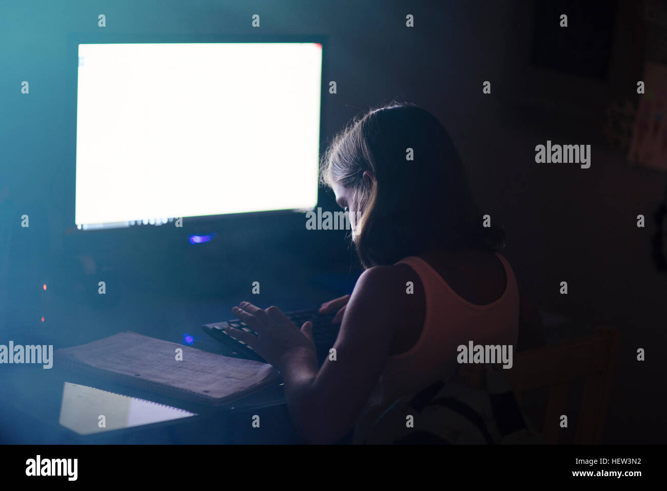 Mädchen mit Computer in schwach beleuchteten Raum Stockfoto