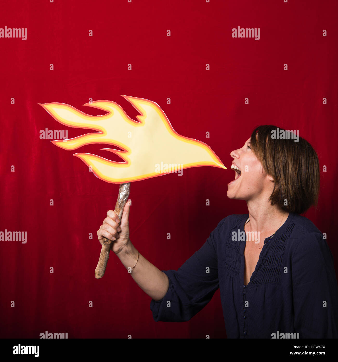 Frau mit Karton ausgeschnittenen Flammen vorgibt, Feuer spucken Stockfoto