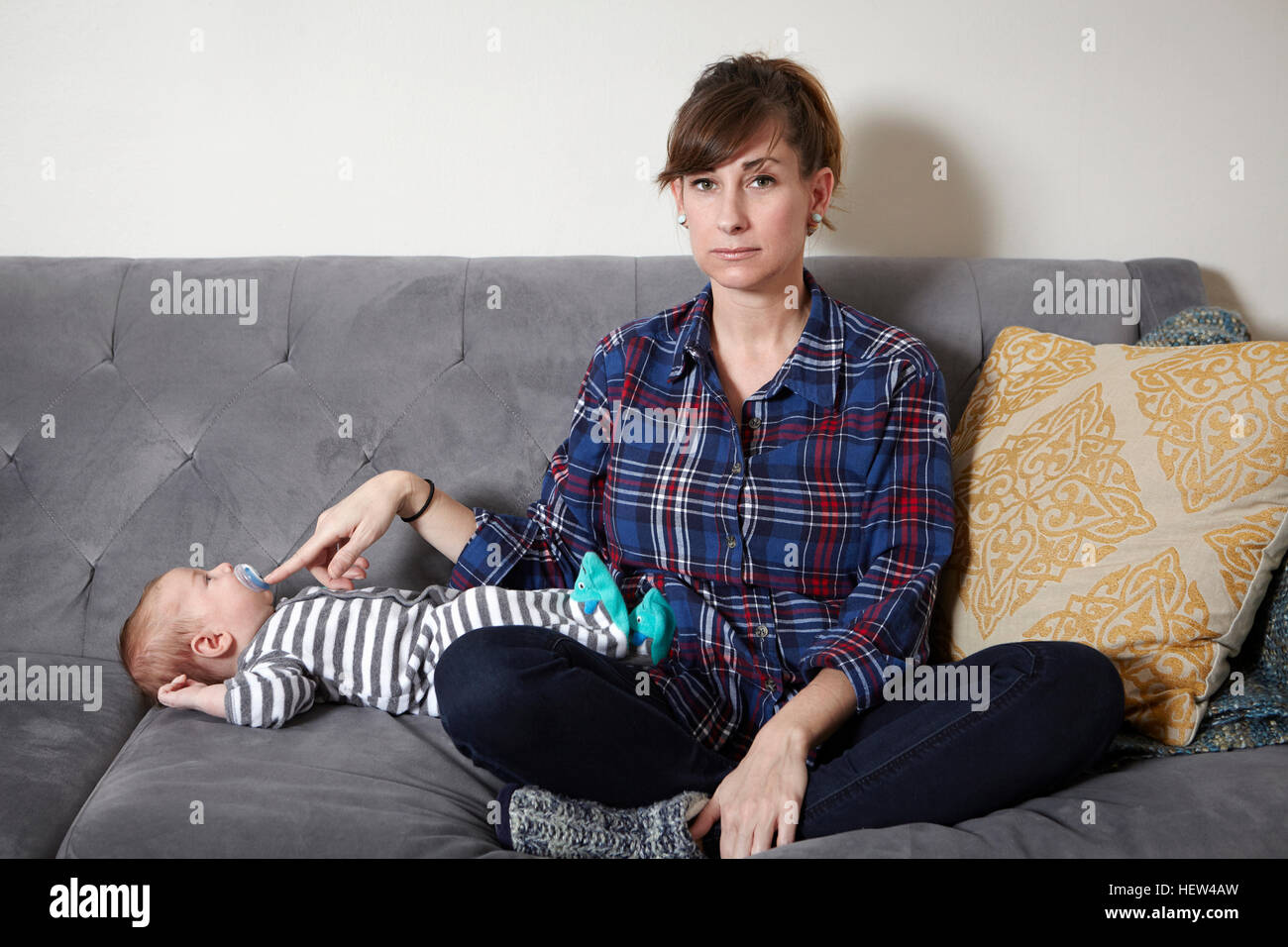 Mutter auf Sofa hält Baby junge Schnuller in Stockfoto