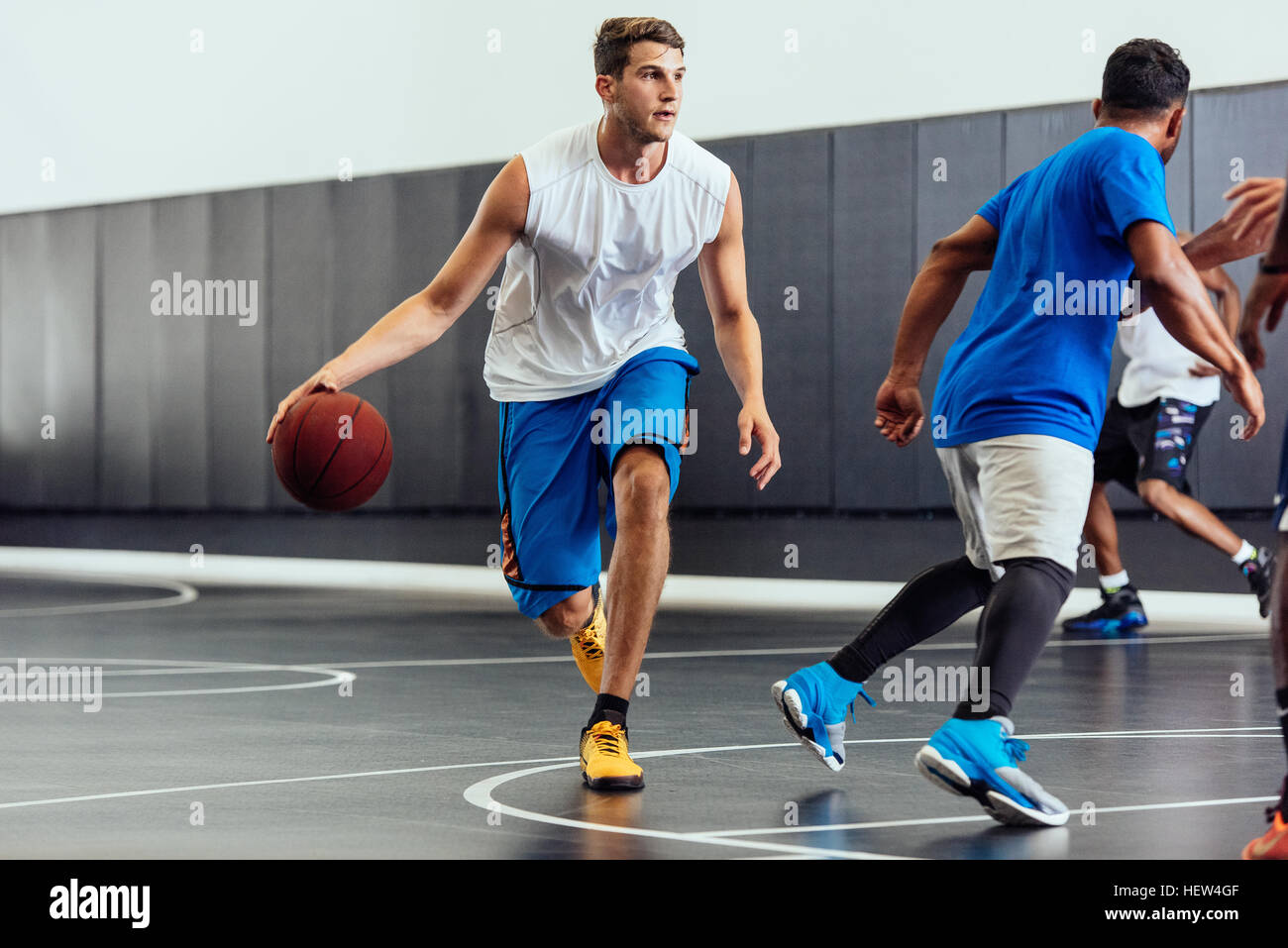Männliche Basketball-Spieler mit Ball in Basketball-Spiel läuft Stockfoto