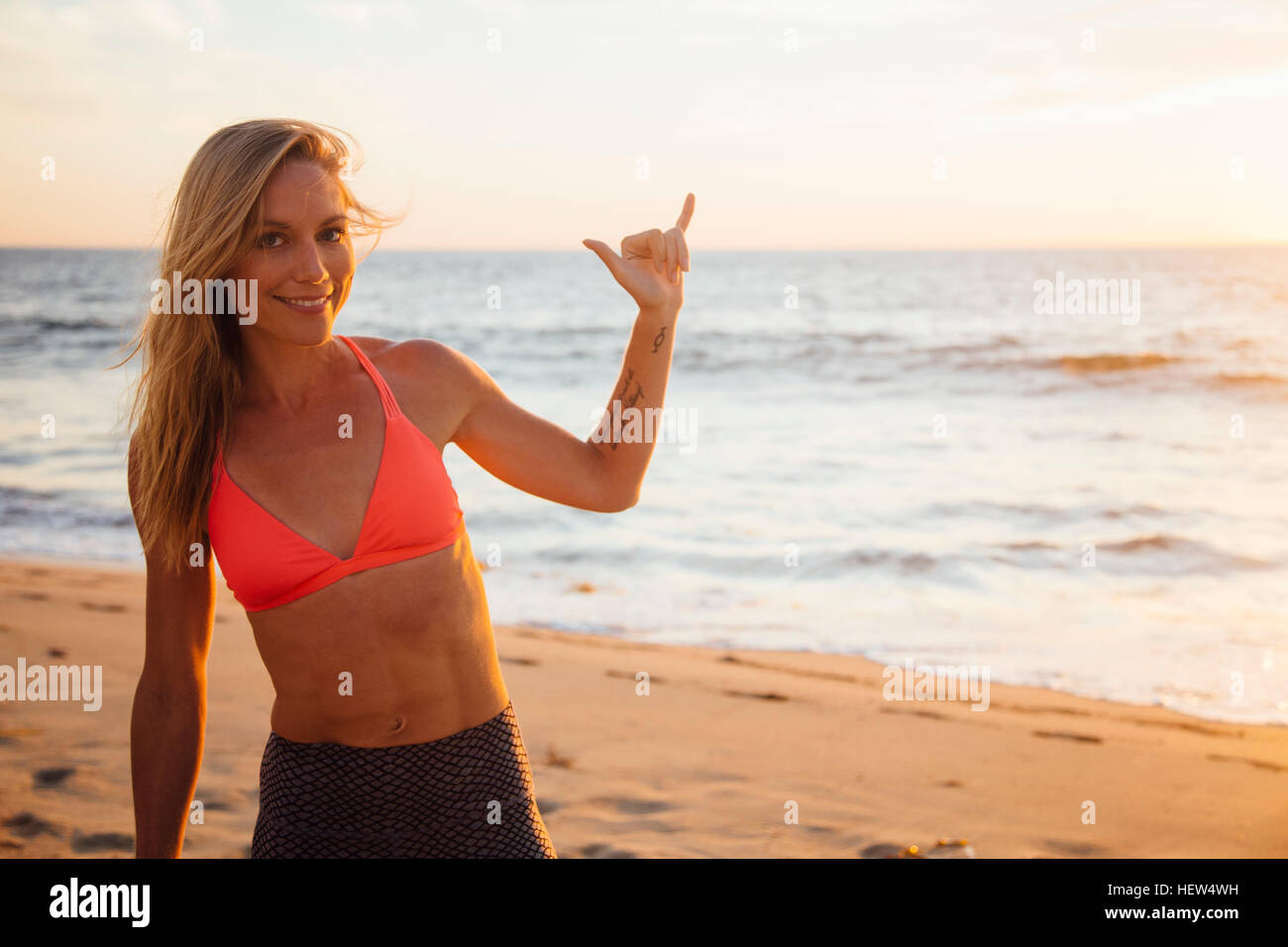 Frau am Strand machen Rock'n'Roll Handbewegung Stockfoto