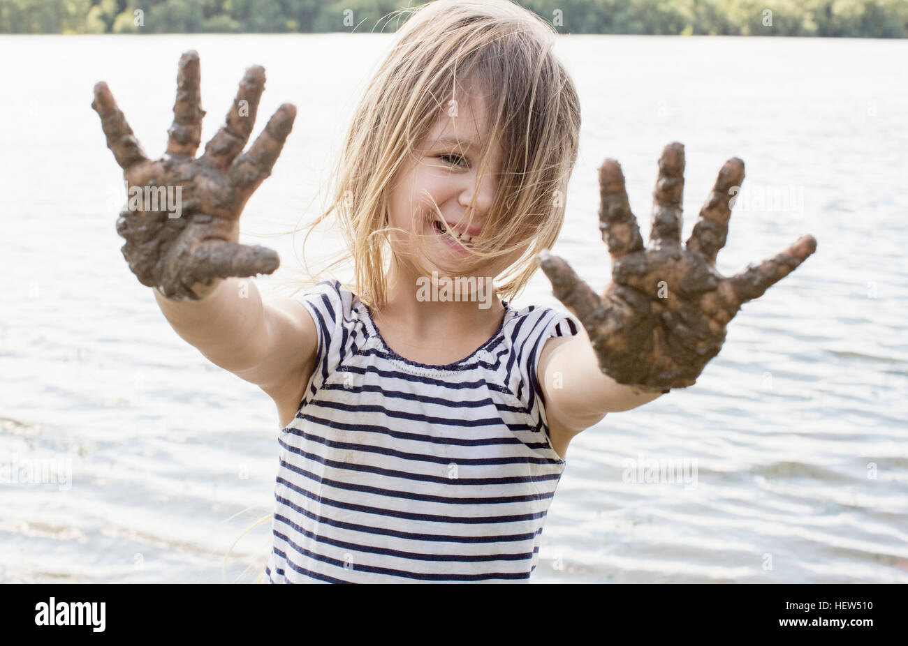 Porträt eines Mädchens mit schlammigen Händen im Fluss Stockfoto