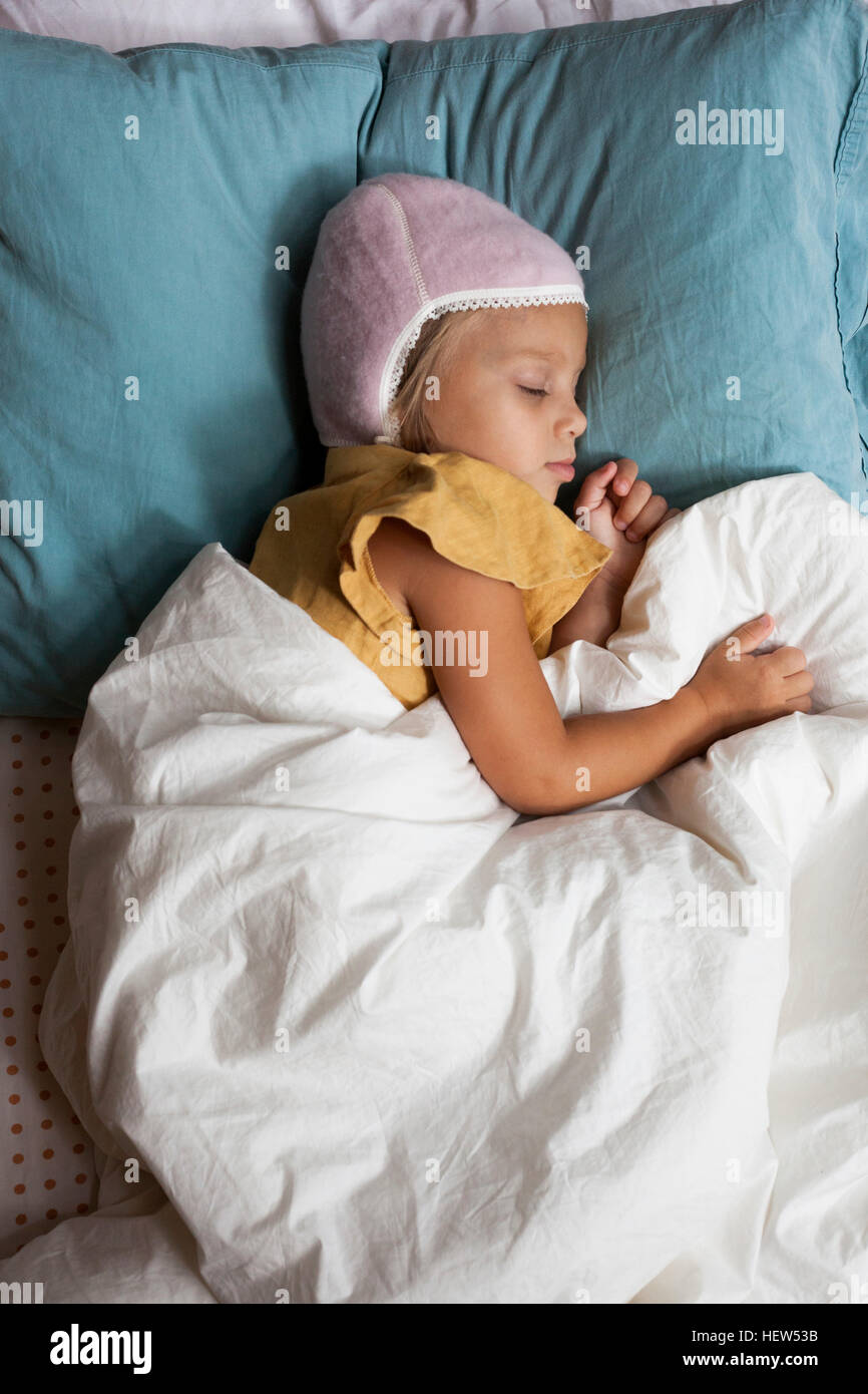 Junges Mädchen schlafend im Bett, warme Mütze tragen Stockfoto