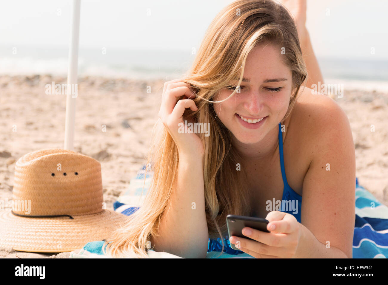 Junge Frau mit Handy am Strand Stockfoto