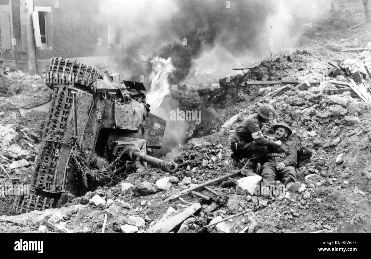 Schlacht von FALAISE GAP August 1944. Eine verwundete britische Soldaten erhält medizinischen Hilfe neben einem brennenden deutsche StuG 3 Tank. Foto: Britischer Offizieller Stockfoto