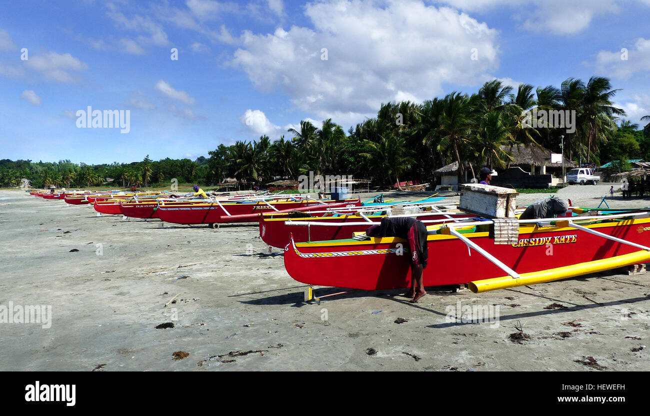 Currimao Beach, nur eine kurze Fahrt von Laoag auf den Philippinen entfernt, bietet eine ruhige und weniger überfüllte Alternative zu bekannteren Stränden wie Pagudpud. Der Strand ist berühmt für seine Kokospalmen und farbenfrohen Bilog-Fischerboote, die malerische Vergnügungsausflüge bieten. Die Küste ist perfekt zum Entspannen und Genießen der Küstenumgebung. Stockfoto