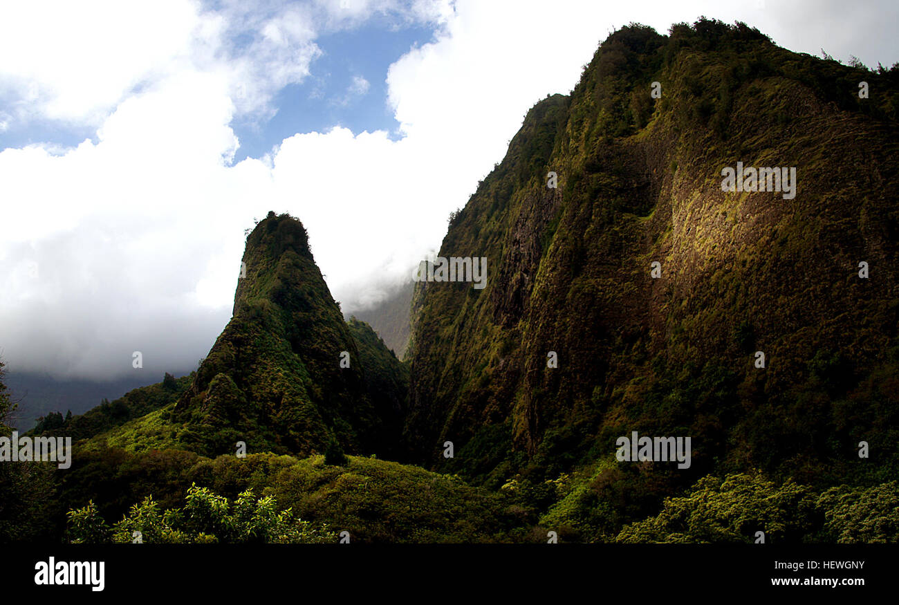 Smaragdene hoch aufragenden Gipfeln bewachen den üppigen Talboden des Iao Valley State Park. Im Central Maui gerade westlich von Wailuku, dieser friedlichen 4.000 Hektar großen, 10 Meilen langen Park ist Heimat einer der markantesten Wahrzeichen von Maui, die 1.200 Fuß Iao Nadel. Dieses kultige grün Jaguaren Felsen zu Tage tretenden überblickt Iao Stream und ist eine ideale Attraktion für einfache Wanderungen und Besichtigungen. Stockfoto