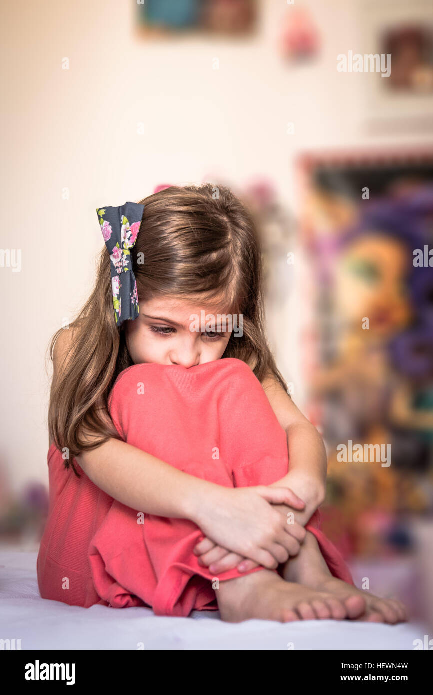 Trauriges Mädchen umarmt Knie Stockfoto