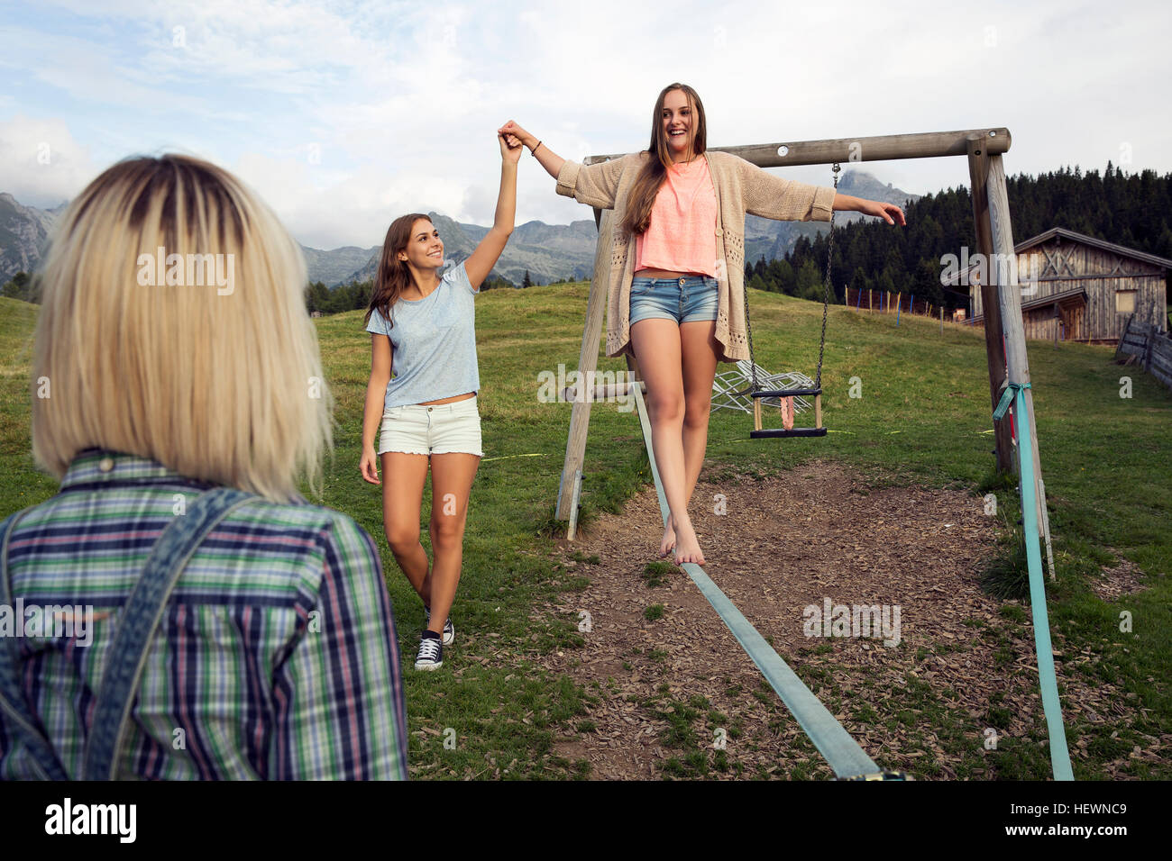 Drei Erwachsene Freundinnen balancieren auf der Slackline in Österreichische Alpen, Sattelbergalm, Tirol, Österreich Stockfoto