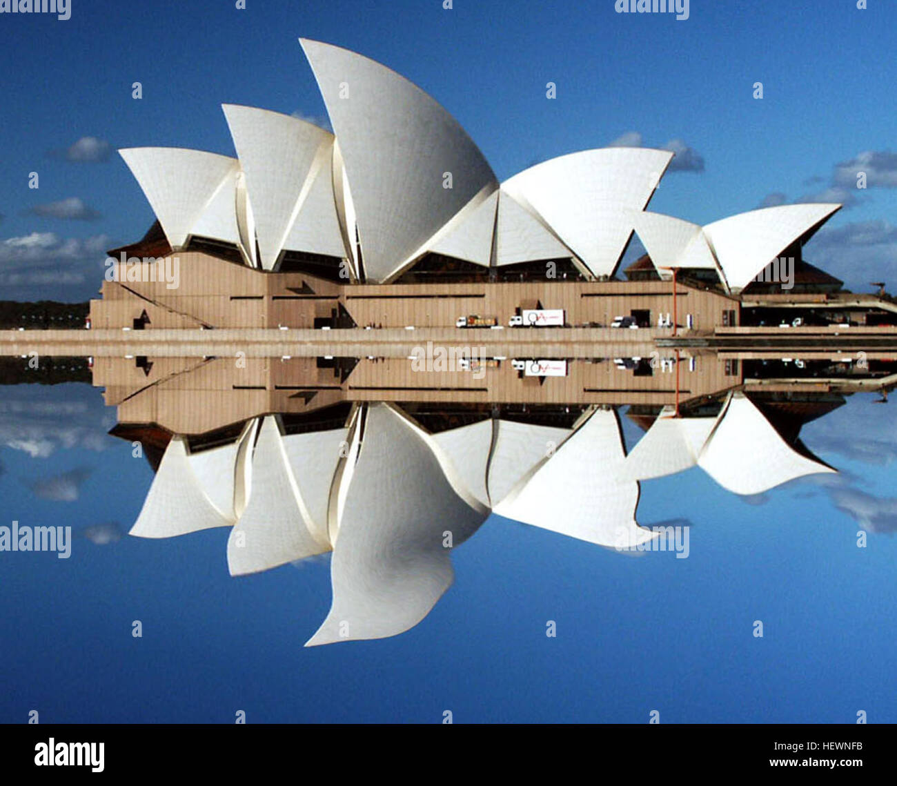 Dieses lebhafte Foto fängt die architektonische Schönheit des Sydney Opera House am Bennelong Point mit seinen berühmten weißen Segeln ein, die sich im umliegenden Wasser spiegeln. Das Bild zeigt auch das nahe gelegene Joan Sutherland Theatre und unterstreicht die kulturelle Bedeutung von Sydneys Uferpromenade. Stockfoto